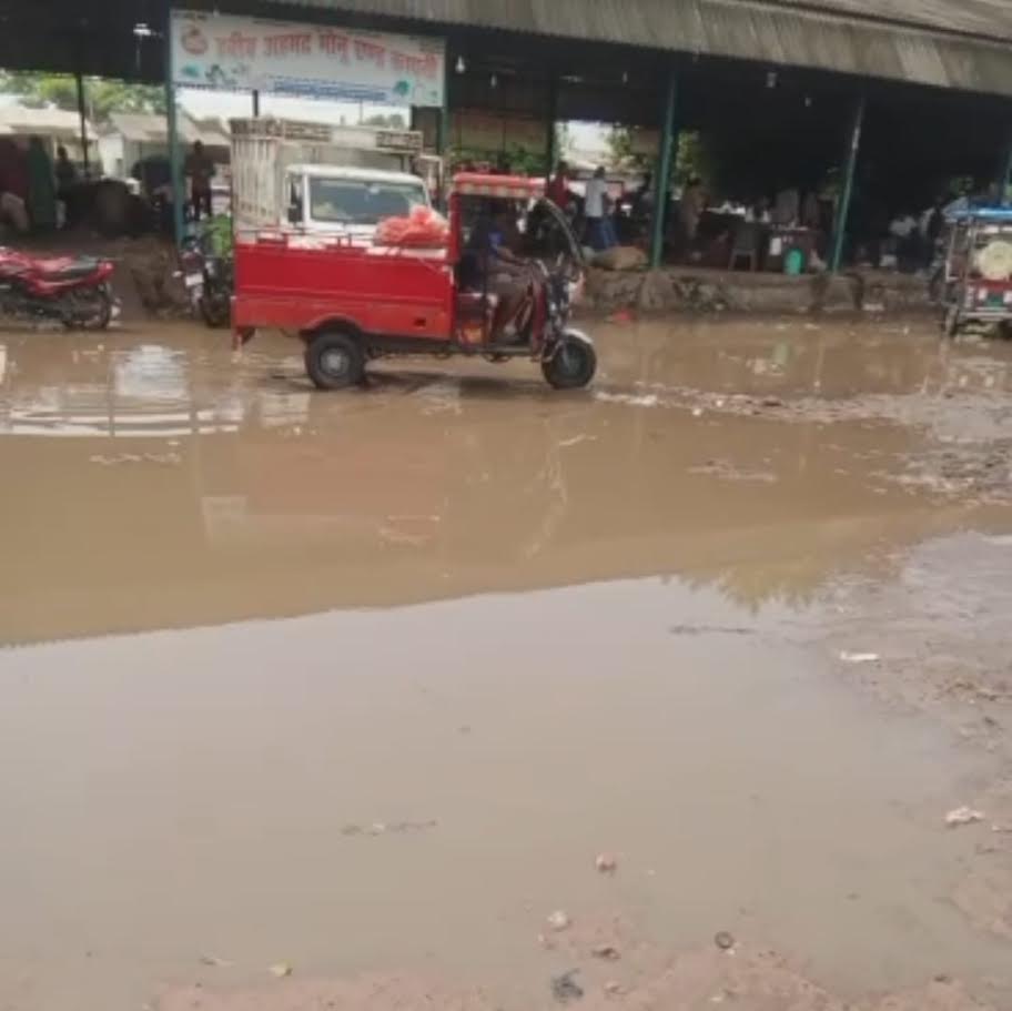 अंबेडकरनगर की सिझौली सब्जी मंडी में बारिश के बाद भरे पानी और कीचड़ के बीच खरीदारी करते लोगों की सांकेतिक तस्वीर।