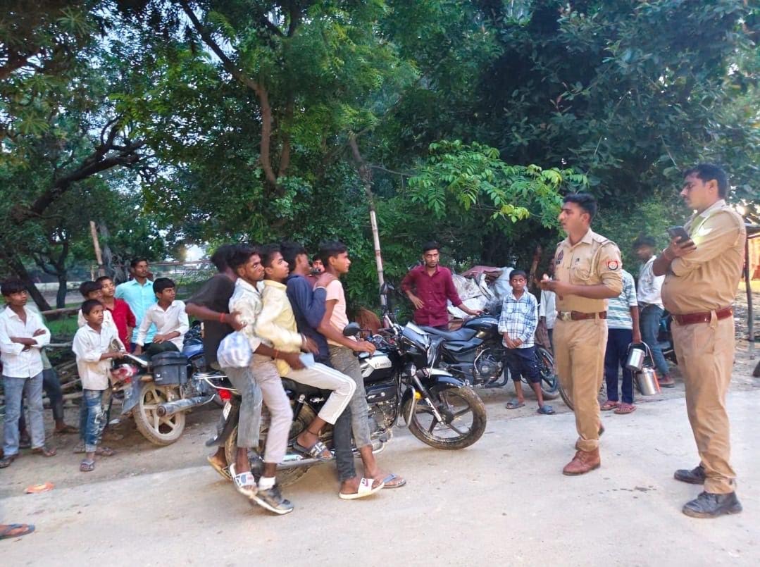 अम्बेडकरनगर के मंशापुर चौराहे पर पांच सवारी बैठी बाइक की जांच करती पुलिस।