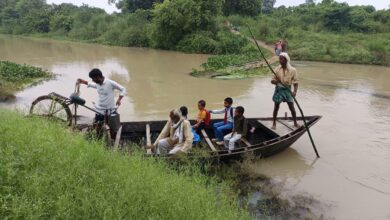 अंबेडकरनगर में टौंस नदी का जलस्तर बढ़ने के बाद नाव से आवागमन करते ग्रामीण।