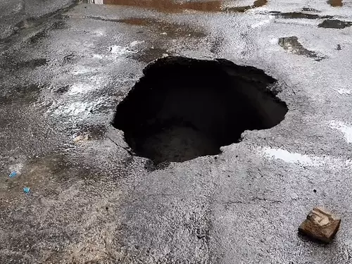 लखनऊ में आईटी चौराहे के पास सड़क धंसने के बाद बैरिकेडिंग किया गया गहरा गड्ढा