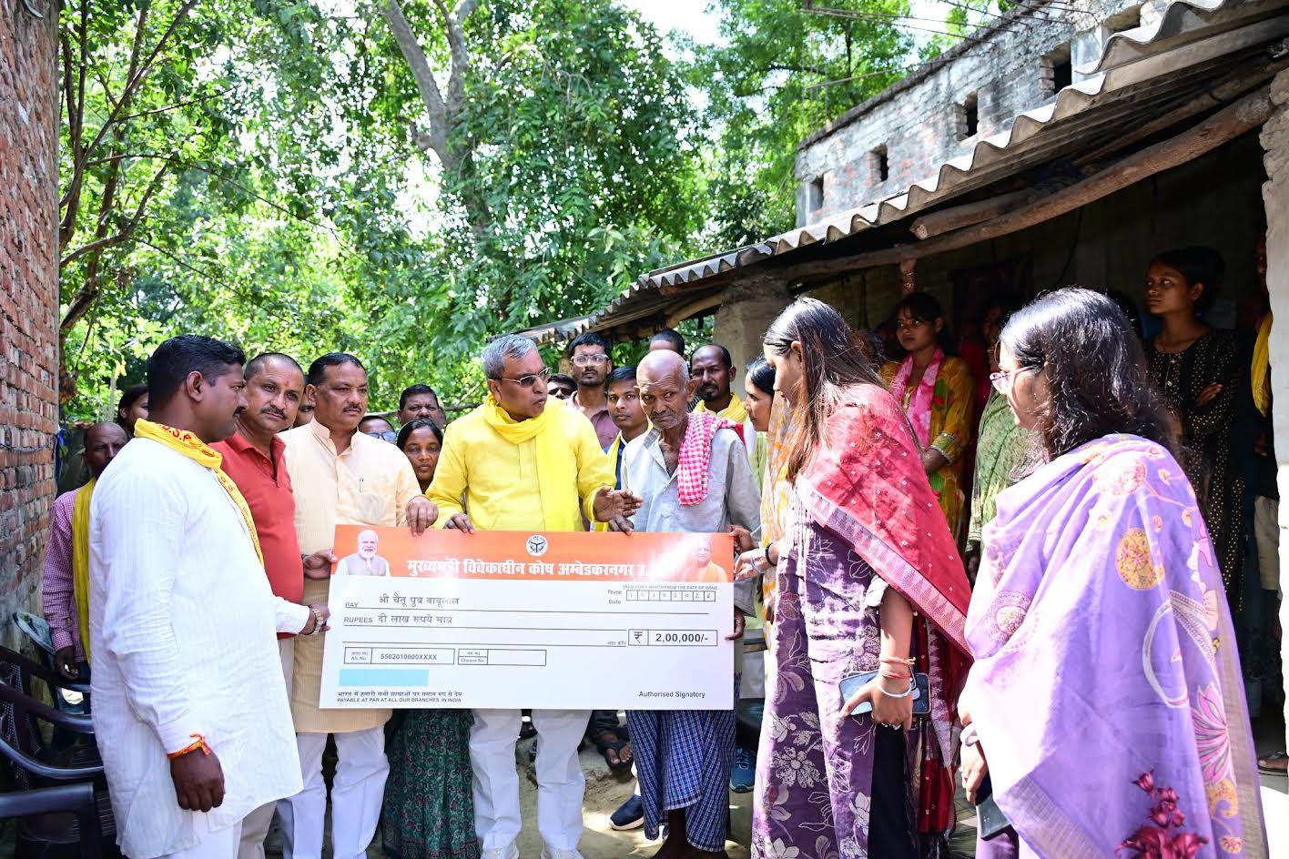 अंबेडकरनगर के कुर्की महमूदपुर गांव में हत्या पीड़ित रामकिशुन के परिवार को मुख्यमंत्री विवेकाधीन कोष से दो लाख रुपये की सहायता का चेक सौंपते प्रभारी मंत्री ओमप्रकाश राजभर और मौजूद अधिकारी।